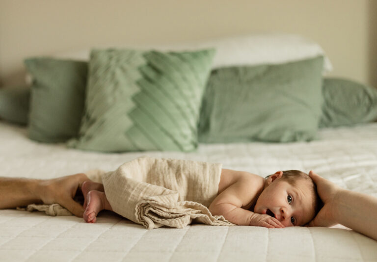 Newborn baby lays on the bed with a neutral tan blanket for Monroe, WA photographer