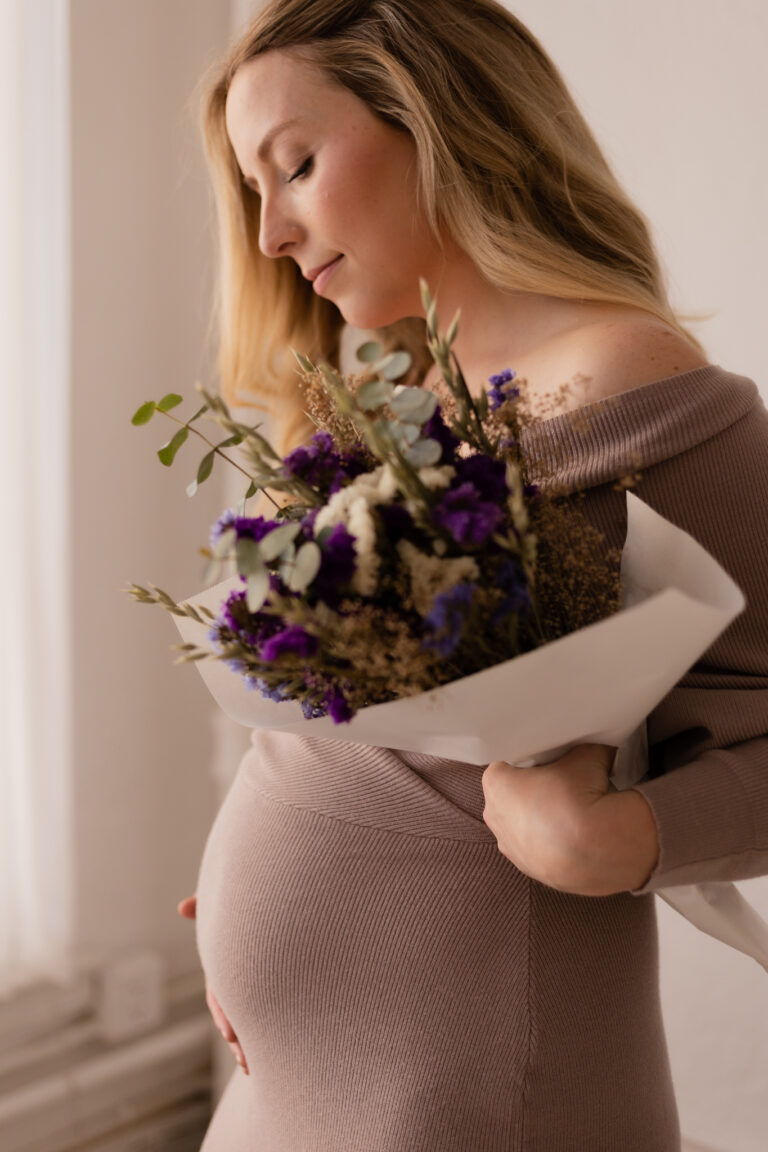 Pregnant mother holding flowers showing her baby bump in her second trimester with second child