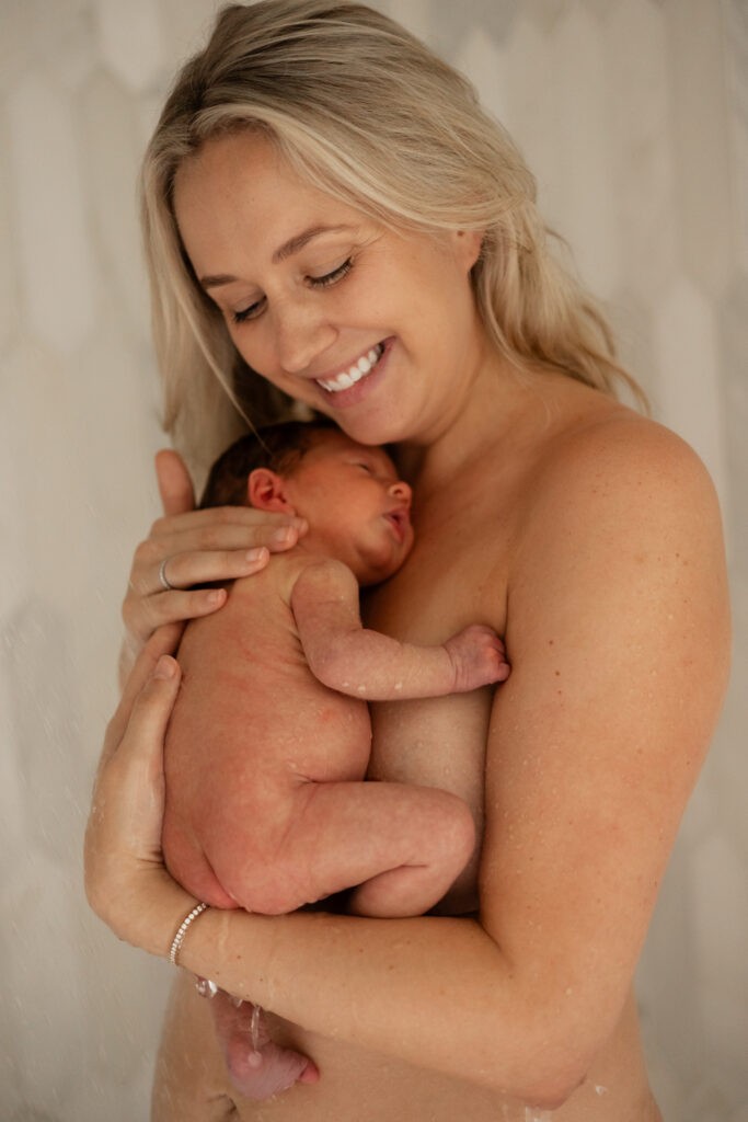 Mother and newborn baby take a shower for a raw motherhood photography session in Seattle
