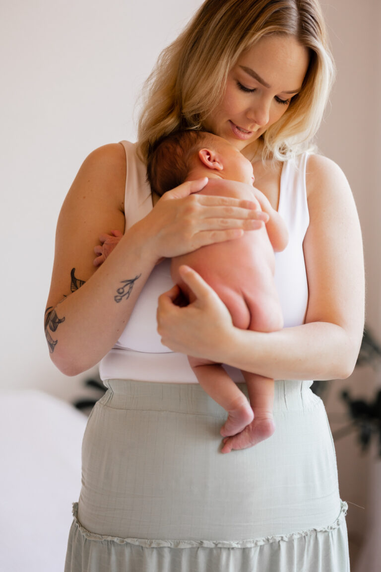 Mother holds naked baby at newborn photography session with Photography by Casey Louise