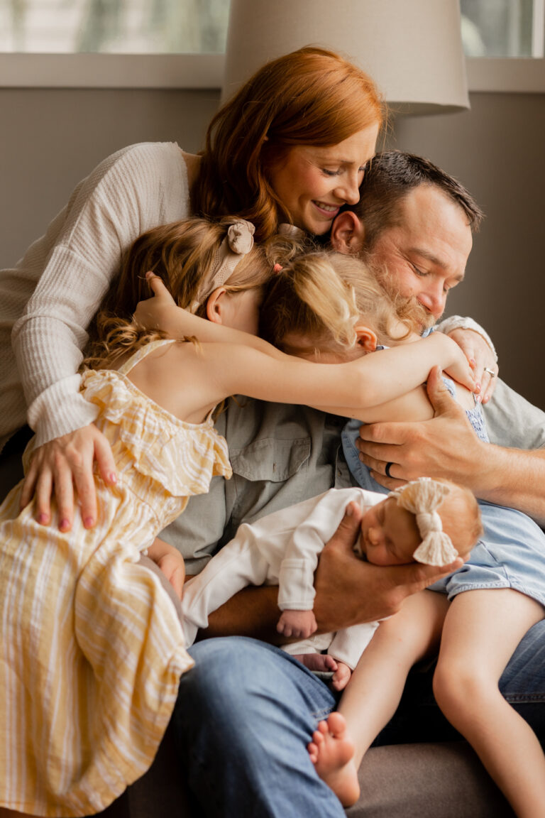Family of five hugs onto each other for photos during their in home newborn photography session in Lake Stevens, WA