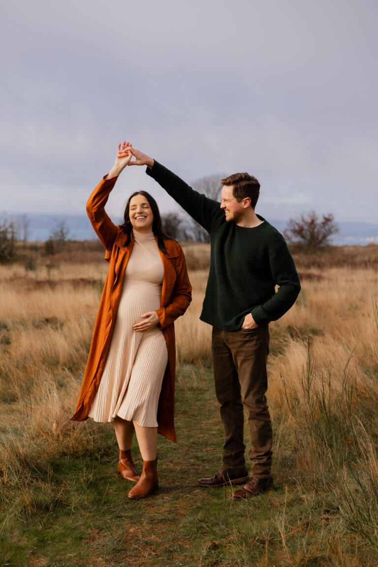 Couple dancing at Discovery park in Seattle for pregnancy photoshoot