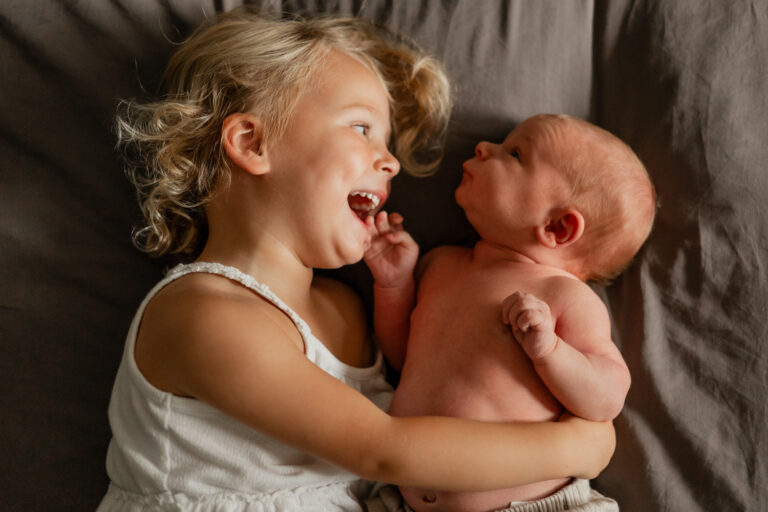 Toddler cuddles newborn brother at in home photography session