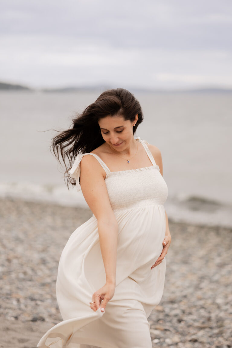 Pregnant mom walks along Golden Gardens beach in Seattle during maternity photography session