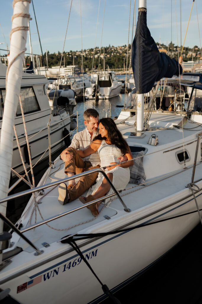Pregnant couple cuddles on their private sail boat in Seattle during maternity photography session