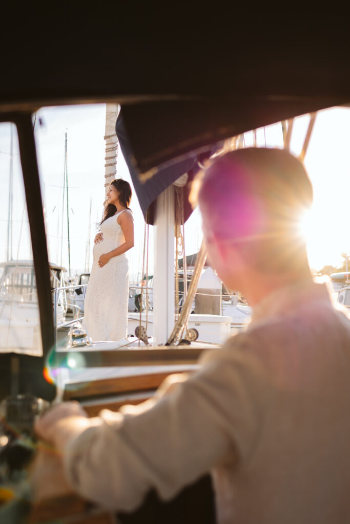 Husband looks at pregnant wife during maternity photoshoot in Seattle on their sail boat