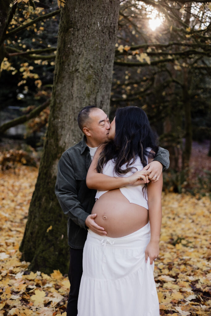 couple kissing at discovery park Seattle during maternity photoshoot