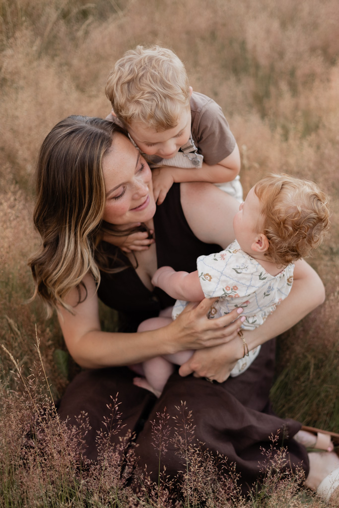 family photography session in Woodinville featuring a mother and her two toddler children hugging and laughing
